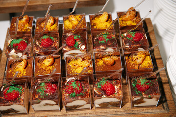  Tiramisu cups topped with fresh raspberries and colorful crumbs served on a wooden platter. Small...