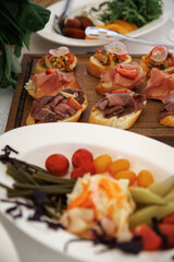 Elegant table setting with a variety of appetizers, fresh fruit, and a lush floral centerpiece. Dishes include assorted cheese, meats, and pastries, creating a festive atmosphere.