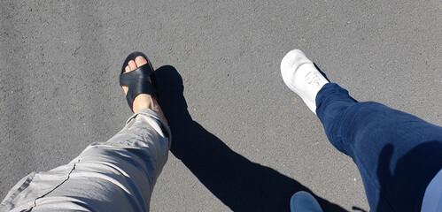 Man and woman walking on asphalt POV,couple's walk in summer,man in slippers woman in sneakers,movement,activity.