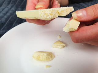 White chocolate,bar, pieces of natural white chocolate on a plate, a woman breaks off white chocolate.