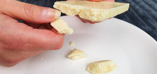 White chocolate,bar, pieces of natural white chocolate on a plate, a woman breaks off white chocolate.