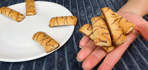 Fresh chocolate covered cookies on a plate,woman holding a cookie,pastry,home cooking.