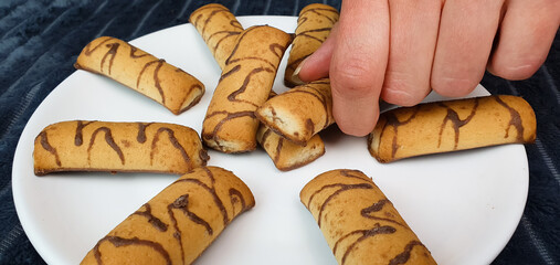 Fresh chocolate covered cookies on a plate,woman holding a cookie,pastry,home cooking.