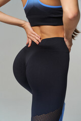 Athletic woman in fitted black and blue activewear, hands on hips. Curved lines of the body emphasize fitness and style. No text present