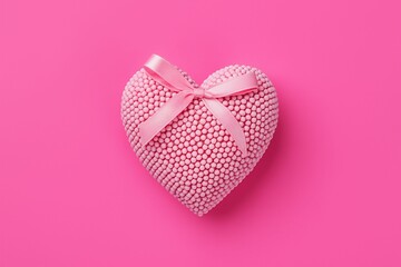 Pink heart-shaped box with white polkdots and pink ribbon tied in bow on top.