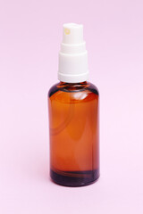 Brown glass cosmetic spray bottle on pink background. Skincare product packaging with pump. Beauty treatment container. Minimalist design for lotion, toner, serum, essential oils or face mist concept.