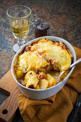 Artisan homemade oven baked French tartiflette with potato and reblochon cheese in a casserole dish...