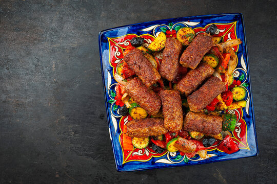 Traditional Croatian cevapcici spicy meat ball rolls with troasted vegetables served  on plate