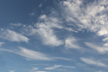 Beautiful wispy clouds drift across a bright blue sky during a sunny afternoon