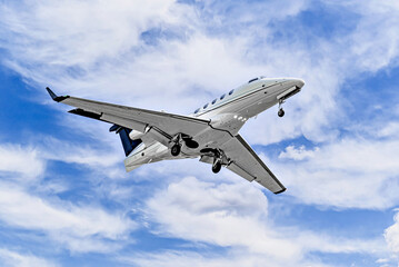 Private business plane flying under a blue sky with white clouds	
