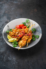 Authentic Sate Ayam - grilled chicken satay sate skewers with stir-fried rice and vegetable served as close-up in a design plate
