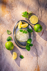 Homemade frozen summer dessert - lime sorbet with fresh peppermint served as top view on a stone board