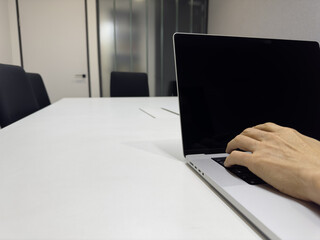Close-up hand on laptop keyboard in modern office meeting room