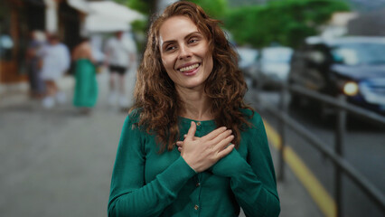 Woman standing on urban street smiling with eyes closed, expressing gratitude in a city...