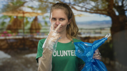 Woman displays hand while pointing as a volunteer blonde young wearing a glove holds a bag for...