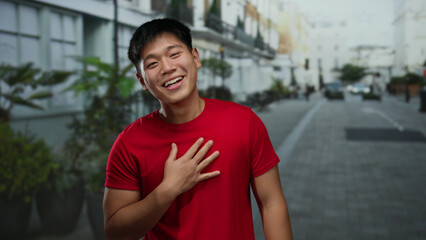 Young man laughing joyfully on a city street wearing red shirt embodying happiness and energy in an...