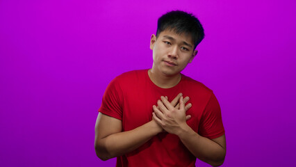 Young man over isolated pink background with hands on heart expressing gratitude or appreciation.