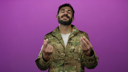 Hispanic man in military uniform makes money gesture with both hands against a vibrant pink...