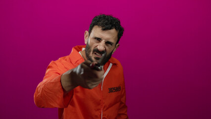 Hispanic man in orange prison jumpsuit holding knife against pink background, evoking danger and tension.