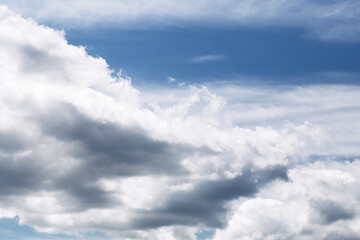 Dramatic cloudy sky background. Beautiful layered clouds in blue sky. Natural weather scene with white and gray formations. Peaceful and moody sky texture. Ideal for design or backdrop projects.