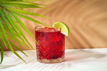 New Yorker red cocktail with whiskey, grenadine, bitter, lime and ice in glass.