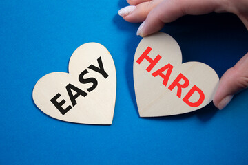 Easy or Hard symbol. Concept word Easy or Hard on wooden hearts. Businessman hand. Beautiful blue...