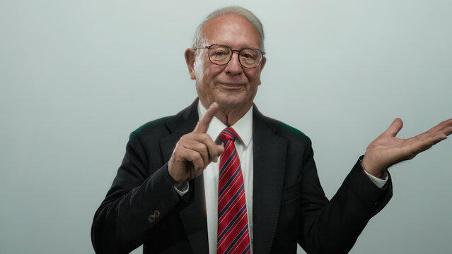 Senior man in business suit gesturing with hand open showcasing isolated concept over white background.