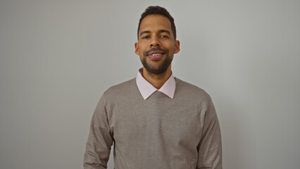Young hispanic man standing isolated against a white background looking handsome and confident wearing a stylish sweater.