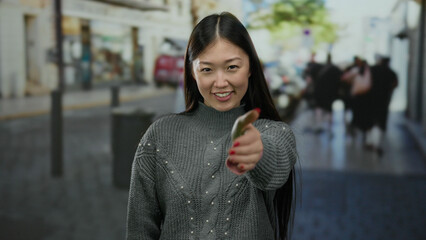 Woman offering handshake on urban street in city setting, showcasing friendly asian female in...