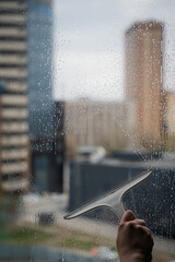 A woman washes a window with a scraper. 