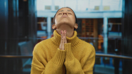 Woman pleading indoors at a hotel with a sad expression dressed in a yellow sweater, embodying...