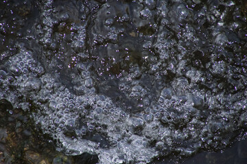 Wasser fliesend mit Blasen in einem Fluss am Abend 1565587797