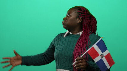 Woman holding dominican flag on green background, expressing emotions through hand gestures,...