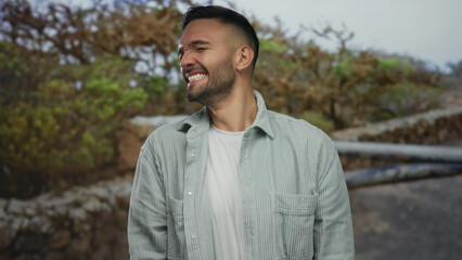 Young man in a park shouting energetically with a joyful expression surrounded by green trees...