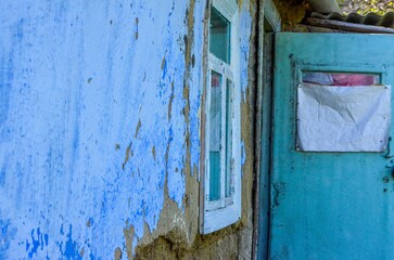 A blue and white house with a window and a door. The door is open and the window is closed