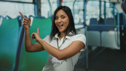 Young woman gesturing and smiling inside a bus, showcasing vibrant movement and expression in a...