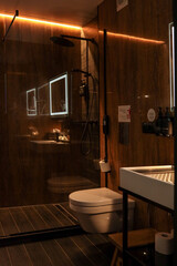 Modern hotel bathroom interior with white sink, toilet, glass shower cabin, illuminated mirror and...
