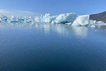 Icebergs floating in a calm blue sea under a clear sky
