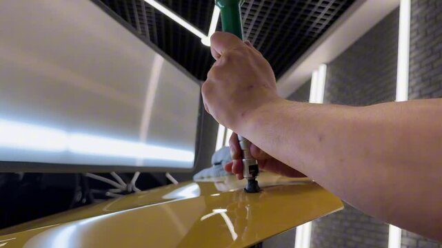PDR. Process of paintless dent repair on car body. The mechanic at the auto shop with tools to repair dents in car body. Body repair. A specialist repairs a dent on the car body without painting.