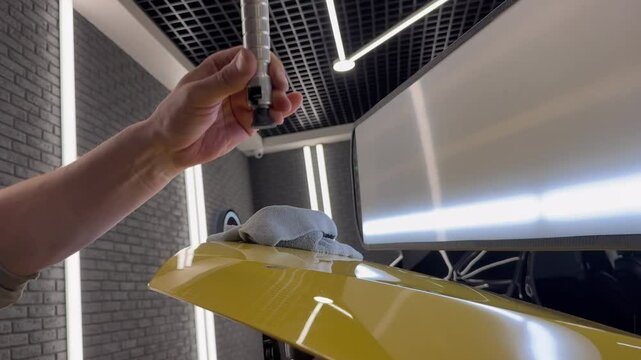 PDR. Process of paintless dent repair on car body. The mechanic at the auto shop with tools to repair dents in car body. Body repair. A specialist repairs a dent on the car body without painting.