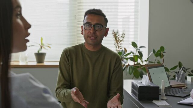 Stressed Indian man talking to alienated female spouse explaining feelings while wife remaining still during couple psychotherapy in counselling office