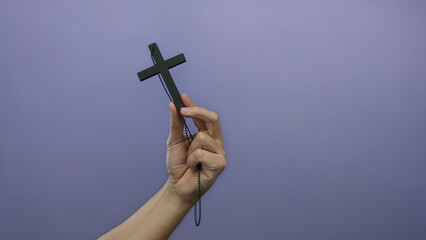 Man holding a cross against a purple background symbolizes faith and spirituality with a minimalist...