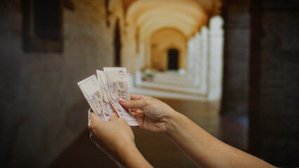 Hands holding singapore dollars in a university hallway, emphasizing business, finance, and...
