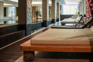 Luxury indoor spa area with modern wooden loungers, pool, stone elements, soft lighting and natural decor. Peaceful atmosphere for relaxation, wellness and rejuvenation