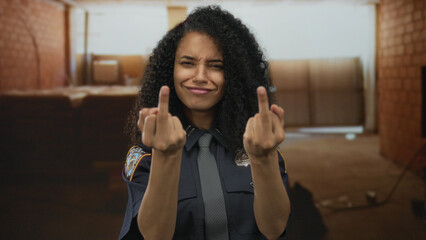 Woman police officer flips middle finger while smiling inside unfinished building; bold attitude...