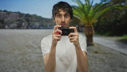 Young man holds gaming controller with fingers pressing colorful buttons in sunny green park;...