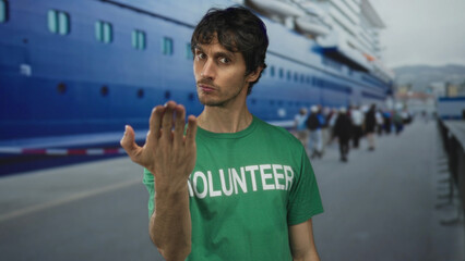 Young volunteer man finger pointing directly at camera at port terminal; community service drive...