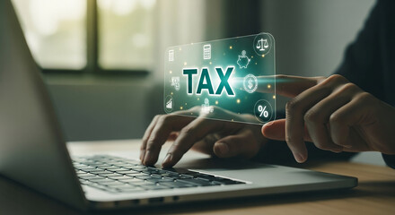 Hands interact with a laptop screen displaying a digital "TAX" interface, showcasing financial data and icons, symbolizing online tax management and digital finance
