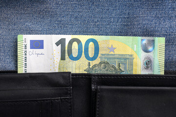 Hundred euro banknote in black leather wallet. Close up of money sticking out from pocket. European...
