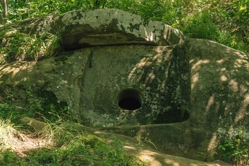 classic stone dolmen built of thick stone slabs with a round hole at the bottom of the outer side...